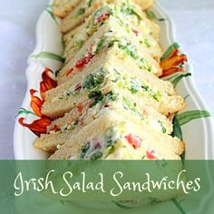 several sandwiches are arranged on a white plate with green and red trimmings along the edges