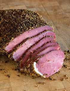 sliced ham sitting on top of a wooden cutting board next to seasoning sprinkles