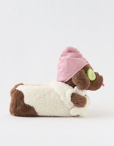 a brown and white stuffed animal with a pink hat on it's head laying down