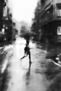 a blurry photo of a person walking down the street in the rain with an umbrella