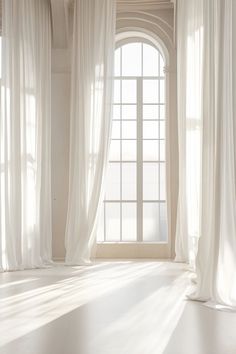 an empty room with large windows and white curtains