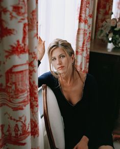 a woman sitting in a chair with her hand on the back of her head and looking at the camera