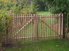 a wooden gate in the middle of a lush green yard