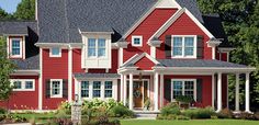 a red house with white trim on the front and side windows is pictured in this image