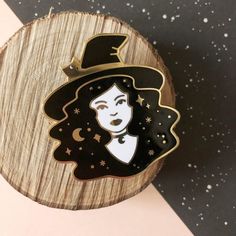 a black and white witch pin sitting on top of a piece of wood with stars