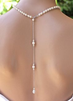 the back of a woman's neck wearing a necklace with pearls and beads on it