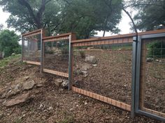 a fenced in area with rocks and dirt on the ground next to it is surrounded by trees