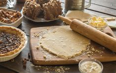 several pies and other desserts on a table with doughnut holes, butter, and cinnamon sticks