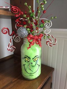 a green mason jar filled with candy canes and an grin face painted on it