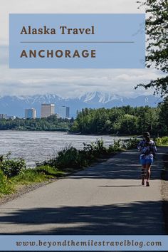 a person riding a bike down a road next to a river with mountains in the background