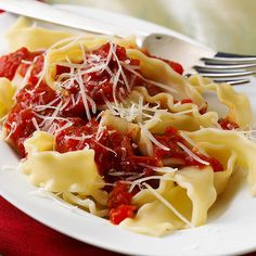 pasta with sauce and parmesan cheese on a white plate next to a fork