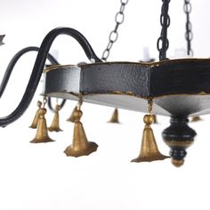 a chandelier that has bells hanging from it's sides and is black with gold trim