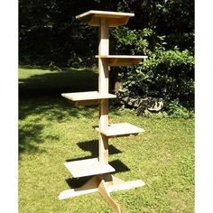 a tall wooden bird feeder in the grass