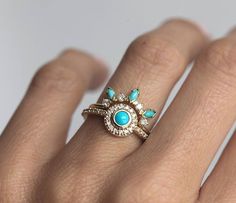 a woman's hand wearing a ring with turquoise stones and diamonds on the band