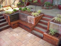 a wooden bench sitting on top of a patio next to a garden filled with potted plants