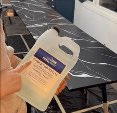 a person holding a gallon of water on top of a black and white marble table