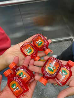 four people are holding small bottles of ketchup on their hands and one person is holding something in the other hand