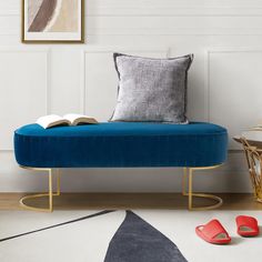 a blue bench with a book on it in front of a white wall and rug