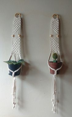 two macrame wall hangings with plants in them