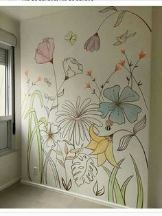 an empty room with flowers painted on the wall and window in the corner behind it