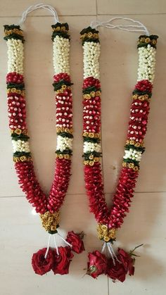 two red and white beads are hanging on the wall next to each other with flowers