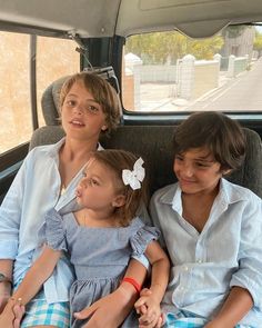 three children sitting in the back of a car