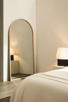 a bedroom with a large mirror on the wall next to a night stand and lamp