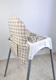 a white and gray checkered highchair with a seat cover on it's back