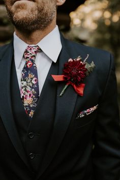 a man wearing a suit and tie with flowers on it's lapel flower