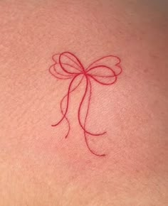 a woman's back with a red bow tattoo on it