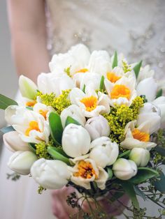 a bride holding a bouquet of white and yellow flowers