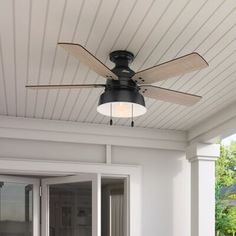 a ceiling fan on the outside of a house with white sidings and wood trim