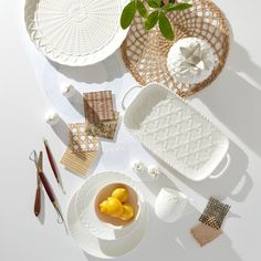 white plates and bowls are arranged on a table with scissors, napkins, and other items