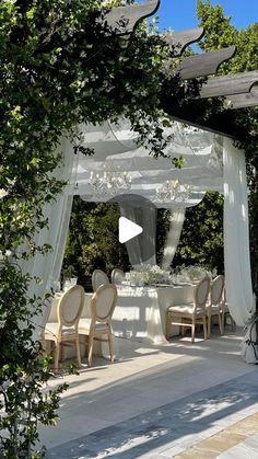 an outdoor dining area with tables and chairs under a pergolated canopy, surrounded by greenery