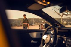 a man standing in the drivers seat of a car