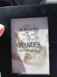 a person holding up a framed photo with the words grandpaa written on it in front of them