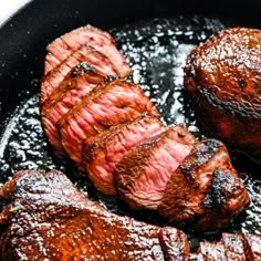 some steaks are cooking in a skillet