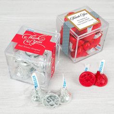 two clear boxes filled with red and white candies next to each other on a table