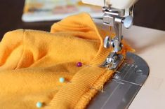 a close up of a sewing machine with a yellow shirt on it's side