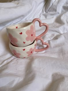 two heart shaped cups sitting on top of a white sheet