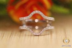 two wedding rings sitting on top of a wooden table next to an orange flower in the background