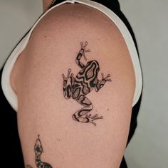 a frog tattoo on the back of a woman's left shoulder and upper arm