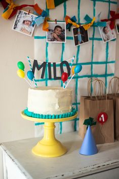 a birthday cake sitting on top of a table next to a party hat and balloons