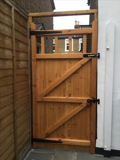 a wooden gate is open on the side of a house