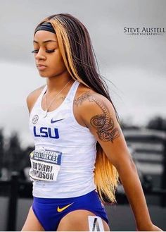 a woman with long hair and tattoos on her arm, wearing a white tank top