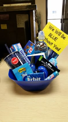 a blue bowl filled with various items on top of a wooden table next to a sign