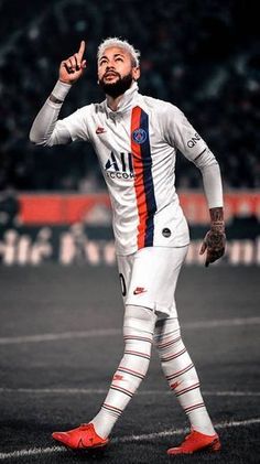 a man in white and orange soccer uniform giving the peace sign with his right hand