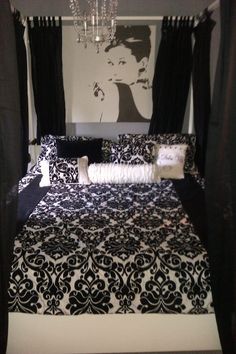 a black and white bed with chandelier hanging from it's headboard