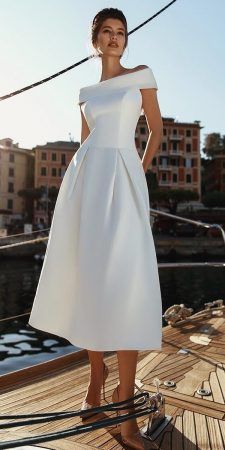 a woman standing on top of a boat wearing a white dress