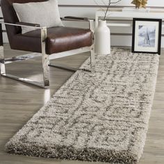 a living room area with a chair, rug and pictures on the floor in front of it